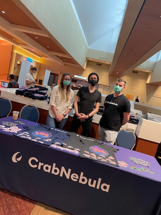 Team members standing behind the CrabNebula booth. From the left: Kassidy, Adam, and Lorenzo.