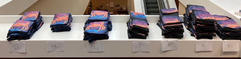 Many stacks of shirts with Nova on them, labeled by size.